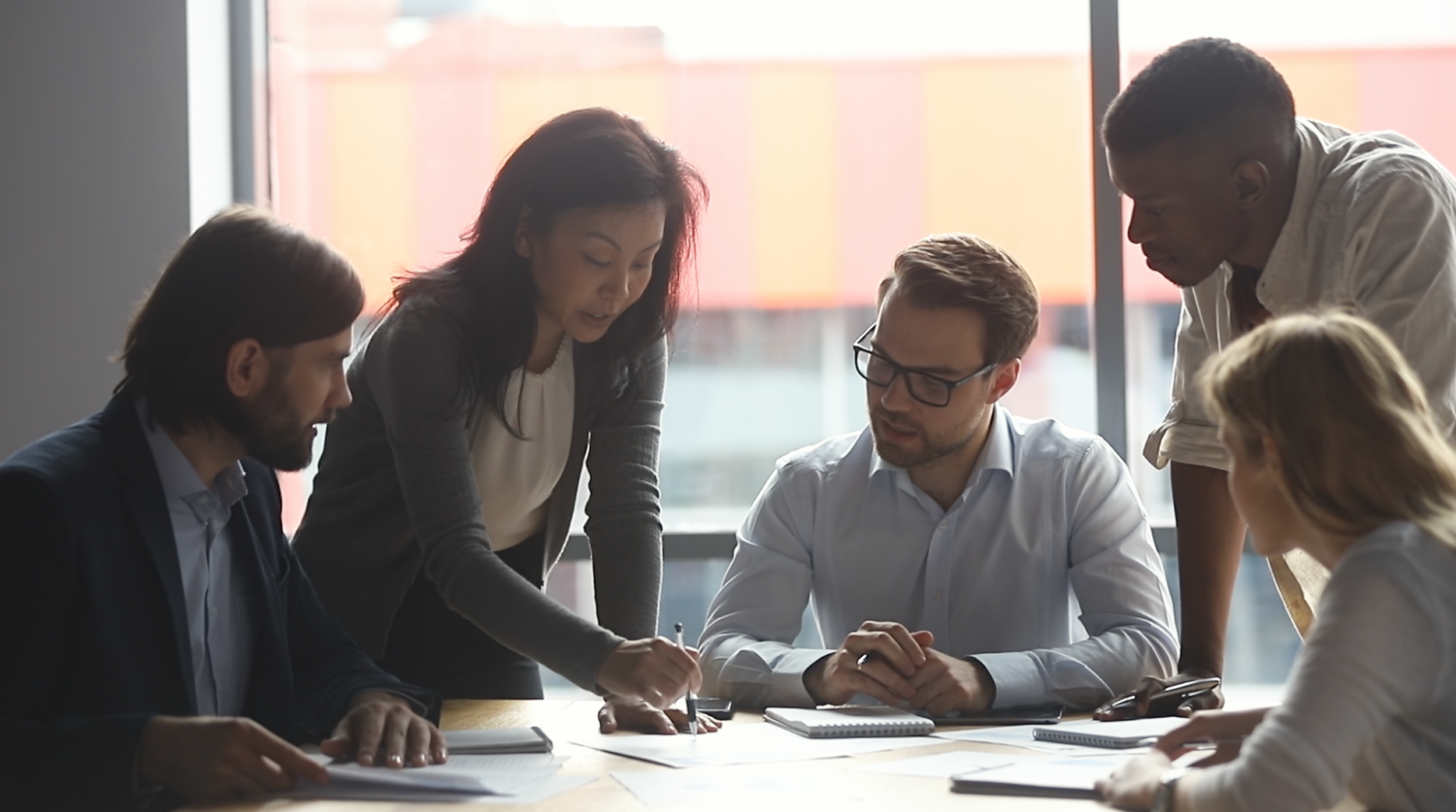 A diverse group of men and women collaborate together at a table.
